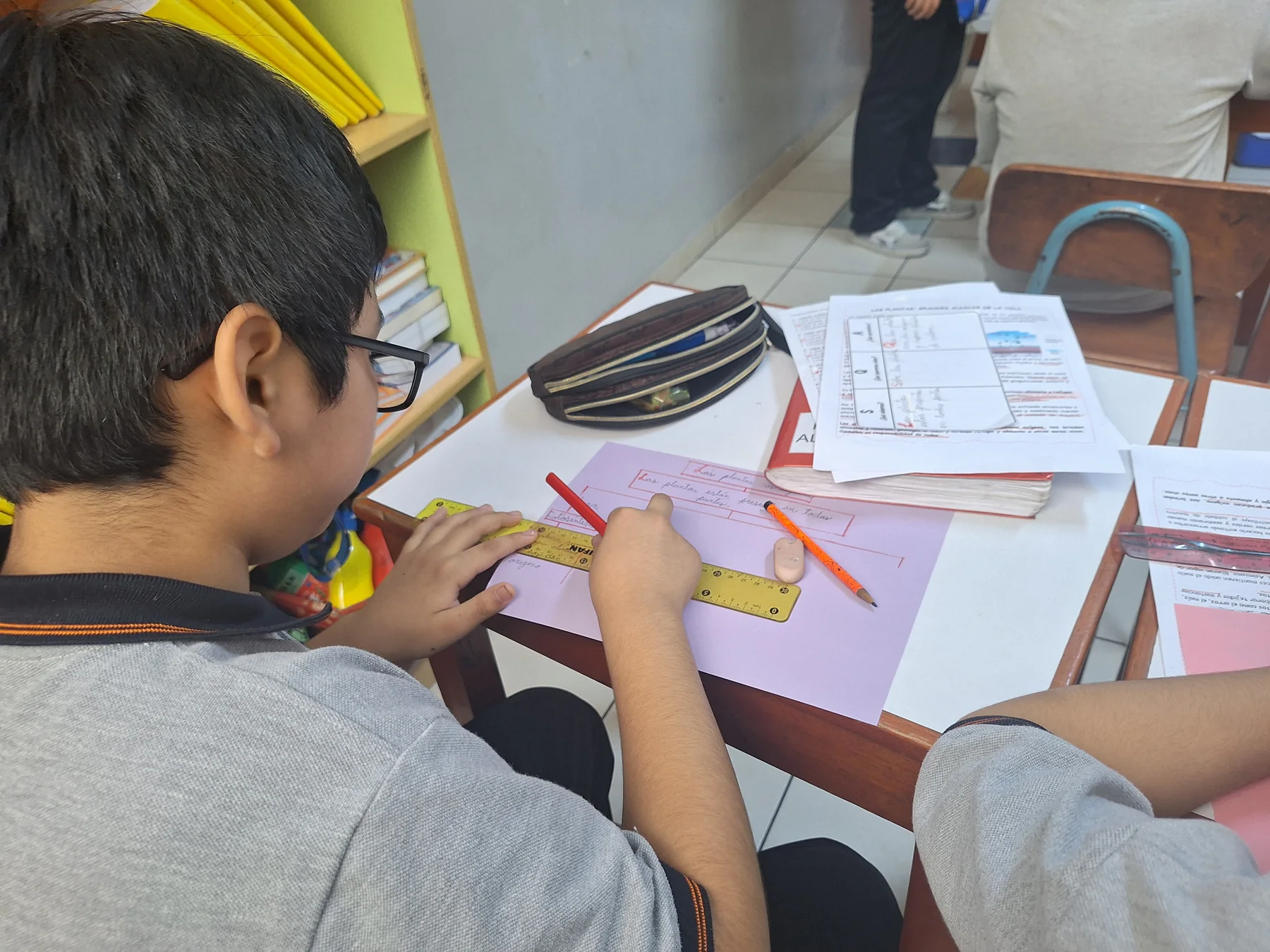 Trabajo con papel y materiales escolares sobre un pupitre